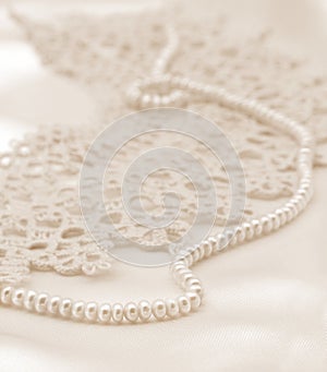 Smooth elegant golden silk or satin with pearls and lace as wedding background. In Sepia toned. Retro style