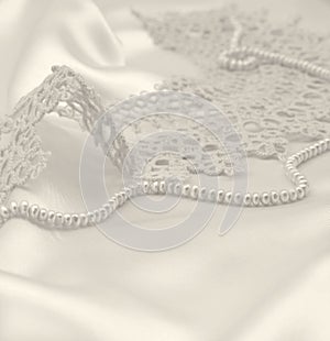 Smooth elegant golden silk or satin with pearls and lace as wedding background. In Sepia toned. Retro style