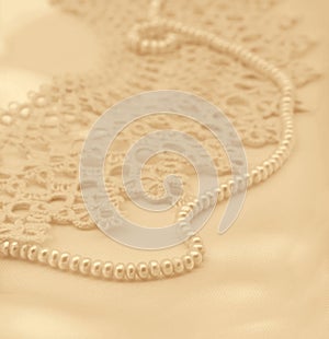 Smooth elegant golden silk or satin with pearls and lace as wedding background. In Sepia toned. Retro style