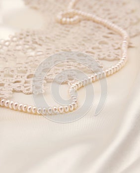 Smooth elegant golden silk or satin with pearls and lace as wedding background. In Sepia toned. Retro style