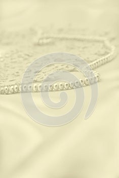 Smooth elegant golden silk or satin with pearls and lace as wedding background. In Sepia toned. Retro style