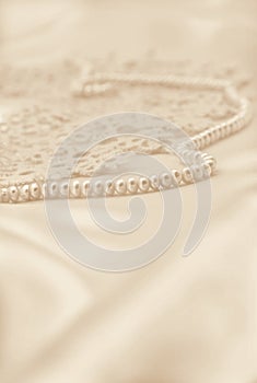 Smooth elegant golden silk or satin with pearls and lace as wedding background. In Sepia toned. Retro style