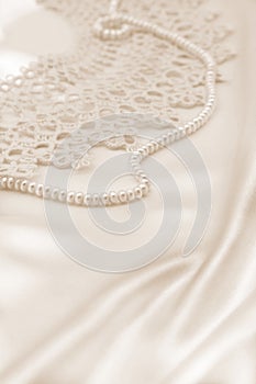 Smooth elegant golden silk or satin with pearls and lace as wedding background. In Sepia toned. Retro style