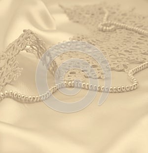 Smooth elegant golden silk or satin with pearls and lace as wedding background. In Sepia toned. Retro style