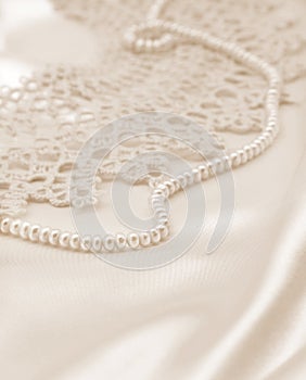 Smooth elegant golden silk or satin with pearls and lace as wedding background. In Sepia toned. Retro style