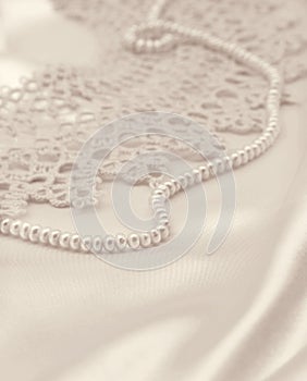 Smooth elegant golden silk or satin with pearls and lace as wedding background. In Sepia toned. Retro style