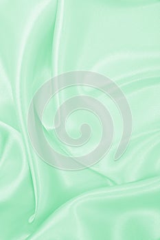 Smooth elegant green silk or satin luxury cloth texture as abstract background. Luxurious background design