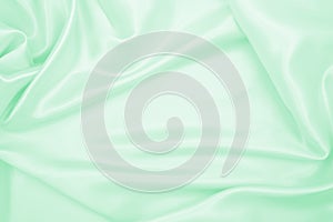 Smooth elegant green silk or satin luxury cloth texture as abstract background. Luxurious background design