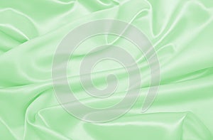 Smooth elegant green silk or satin luxury cloth texture as abstract background. Luxurious background design