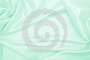 Smooth elegant green silk or satin luxury cloth texture as abstract background. Luxurious background design