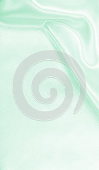 Smooth elegant green silk or satin luxury cloth texture as abstract background. Luxurious background design