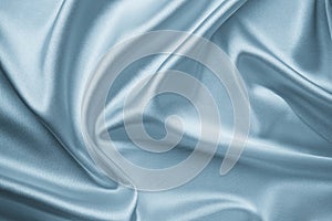 Smooth elegant silver silk fabric background. Metallic gray color of shiny textile, texture. Satin folds, waves pattern. Silky