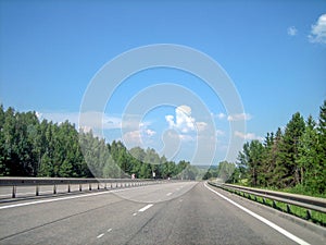 A smooth, flat highway runs forward through the forest