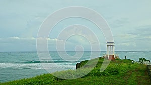 smooth panorama from blue ocean with strong waves to white gazebo on green hill