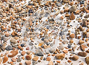 Smooth round pebble stones on the sand beach backgound