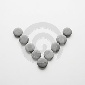 Smooth round pebbles arranged in a symmetrical V shape on a white background