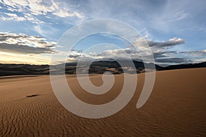 Smooth Sand Dunes and Mountains Enveloped in Clouds