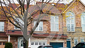 Smooth shot of grey stucco luxury house with big trees and parking. Double decker with big windows, parking and garage