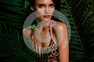 Smooth skin girlfriend stand among palm tree woods exotic island dark night wear fashionable leopard print bikini bra
