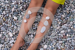 Smooth stones line up on tanned legs against a pebble beach, an ode to nature& x27;s spa. It echoes our inherent