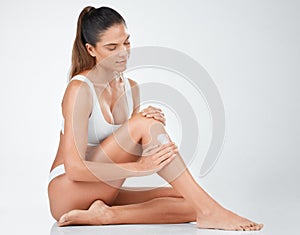 Smooth supple skin is all that I want. Shot of a woman applying lotion to her legs against a studio background.