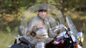 Smooth transition of focus from bokeh to a biker in medieval knight`s armor sits on a motorcycle