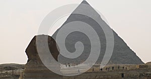 Smooth transition from the Sphinx to the Great Pyramid of Giza in Cairo, Egypt. Clear day, tourists in the background