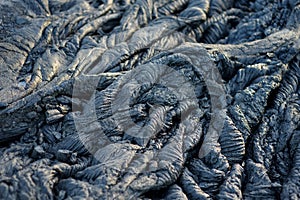 Smooth, undulating surface of frozen pahoehoe lava. Frozen lava wrinkled in tapestry-like folds and rolls resembling twisted rope