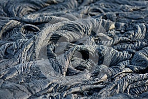Smooth, undulating surface of frozen pahoehoe lava. Frozen lava wrinkled in tapestry-like folds and rolls resembling twisted rope photo
