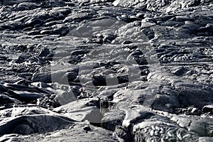 Smooth, undulating surface of frozen pahoehoe lava. Frozen lava wrinkled in tapestry-like folds and rolls resembling twisted rope photo