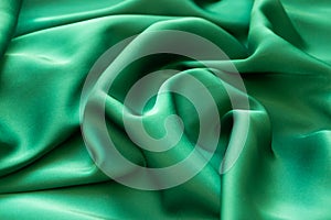 Smooth wavy elegant emerald green silk or satin luxury cloth texture background