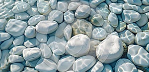 Smooth white pebbles submerged in clear blue water, reflecting sunlight