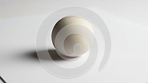 Is placed on a flat white surface casting a soft shadow on its