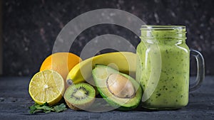 Smoothie of avocado, banana, kiwi and lemon on a wooden table against a black wall. Vegetarian food for a healthy lifestyle.