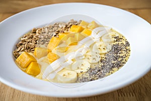 Smoothie bowl with Banana, coconut, mango, granola and chia seeds