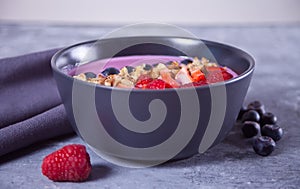 Smoothie bowl with berries and muesli on the gray table