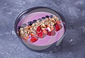 Smoothie bowl with berries and muesli on the gray table