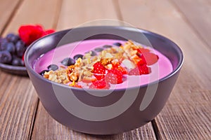 Smoothie bowl with berries and muesli on the wooden table