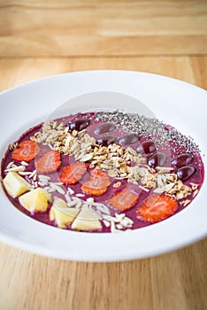 Smoothie bowl with blended berry yogurt, pineapple, grapes, strawberry, chia seed and almond flakes