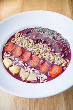 Smoothie bowl with blended berry yogurt, pineapple, grapes, strawberry, chia seed and almond flakes
