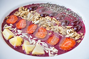 Smoothie bowl with blended berry yogurt, pineapple, grapes, strawberry, chia seed and almond flakes