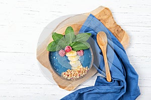 Smoothie bowl with blue spirulina and fresh fruits in a shape of palm tree, healthy breakfast idea, food for kids, top view