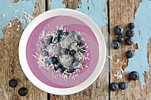 Smoothie bowl with blueberries, dragon fruit, coconut, over rustic wood