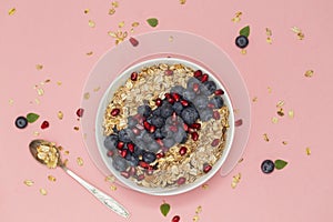 Smoothie bowl with blueberries, pomegranates and granola. Breakfast smoothie bowl on pink background, top view.