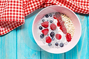 Smoothie bowl with chia seeds, muesli, jam and berries on blue wood background