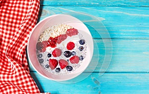 Smoothie bowl with chia seeds, muesli, jam and berries on blue wood background