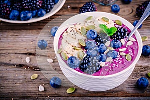 Smoothie bowl with fresh blackberries, blueberries, banana, sunflower seeds, pumpkin seeds, chia seeds and coconut