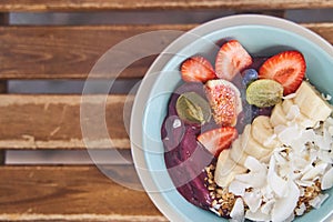 Smoothie bowl with fresh fruit, berries and muesli on the background of a table.