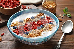 Smoothie bowl with goji berries and spoon on table