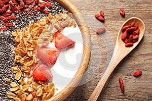 Smoothie bowl with goji berries and spoon on wooden table